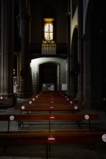 A vertical shot of wooden church benches with signs of social distancing
