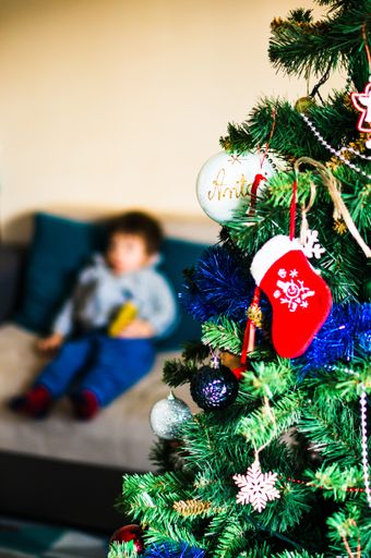 A closeup shot of a decorated Christmas tree with a kid in the blurred background
