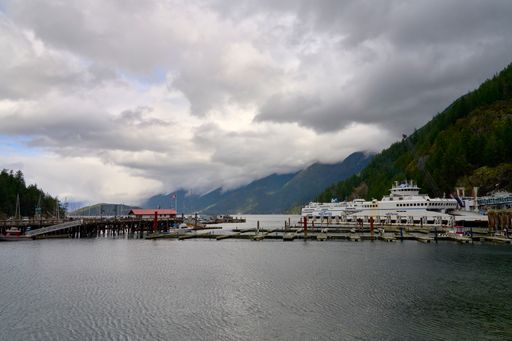 The BC Ferry Horseshoe Bay terminal with two docked ferries and beautiful mountain background with dramatic clouds in the sky.