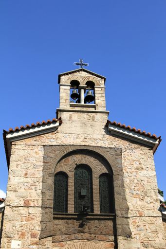 A vertical shot of an ancient church with a tower and two bells atop in Athens, Greece