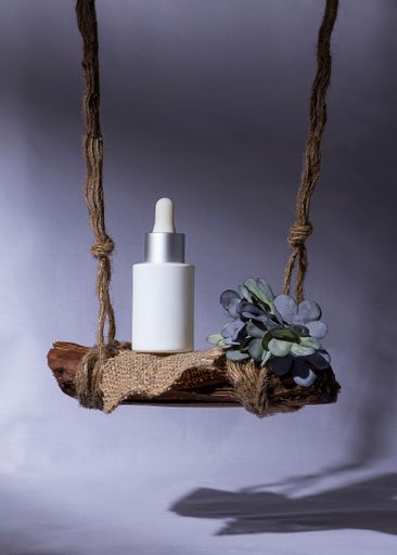 A vertical shot of a white serum bottle on a decorated swing