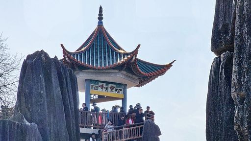 A Group of individuals standing on a pagoda in Shilin Stone Forest in China
