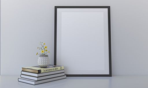 A frame with a blank canvas, books, and a potted flower on them