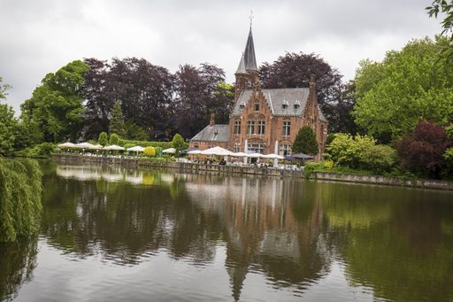 A historic building near the lake surrounded by trees on a gloomy day