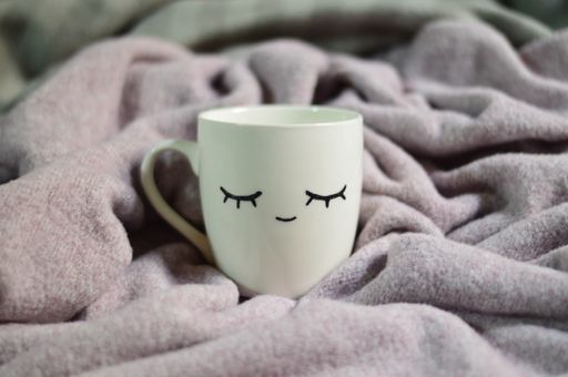 A closeup shot of a white cup on a purple blanket background