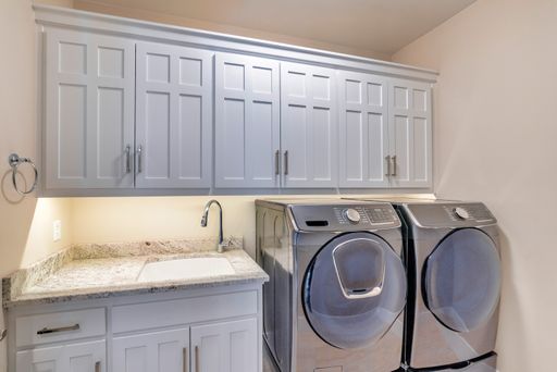 A laundry room with a washing machine, a dryer, and wooden cabinets for clothes
