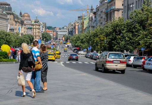 The tourists walking through Wenceslas Square in Prague and enjoying a beautiful street view