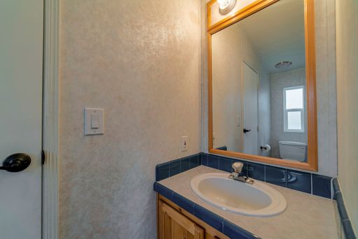 a white sink with wooden-framed mirror and white wall