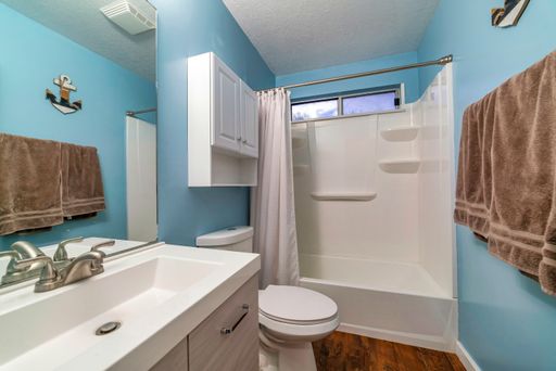 A mirror, a sink, and a bath with curtains in a bathroom