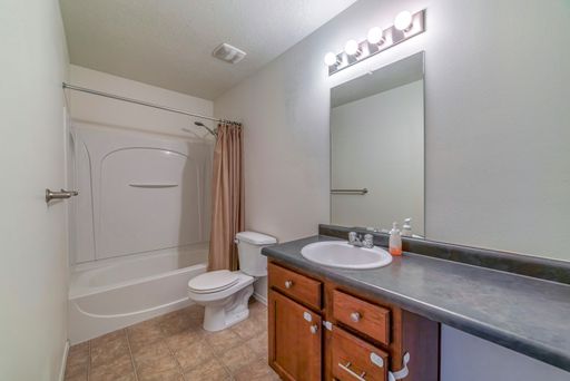 A modern bathroom with a flush toilet, sink and a bathtub with a shower curtain