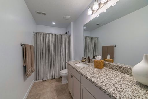A modern bathroom with a sink and a bathtub with a closed shower curtain