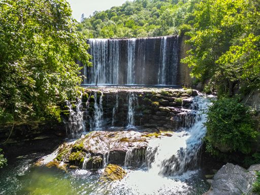 Waterfalls cascading near a serene lake in a forest