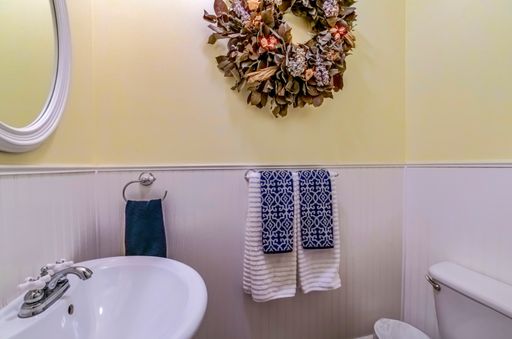 a decorated yellow-white bathroom with sink, mirror and towels