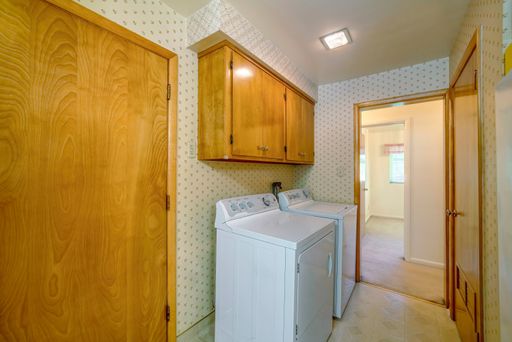 A laundry room with a washing machine, a dryer, and wooden cabinets for clothes