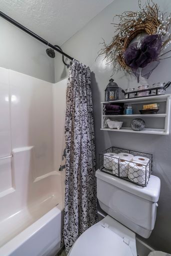 a vertical shot of a flush toilet with an open-curtained bathtub