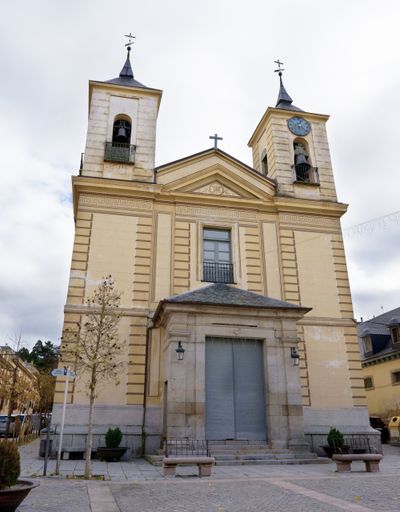 The church is tall and has a bell tower. The building is yellow and has many details. The farm of San Idelfonso. Segovia. Spain. 14-11-23