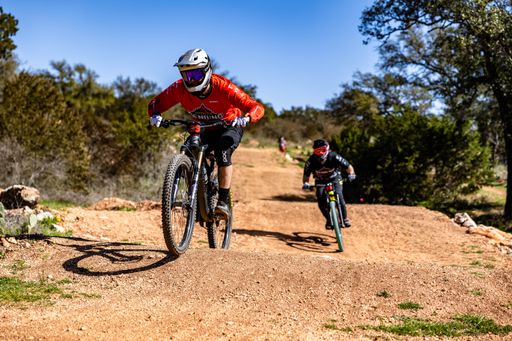 The dirt bikers riding over grassy hills in a rural landscape in Burnet, United States