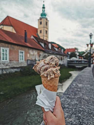 Personal perspective of man holding ice cream cone in street of city of Samobor in Croatia.