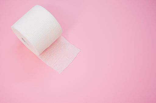 a top view of a sterile gauze bandage roll isolated on a pink background on the left side