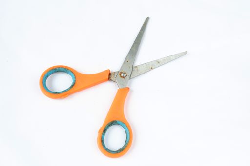 A closeup shot of scissors with orange handles isolated on a white background