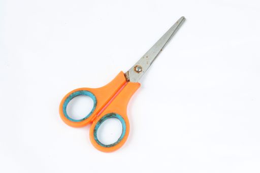A closeup shot of scissors with orange handles isolated on a white background