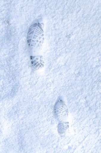 A vertical top view of two shoe prints in fresh white snow