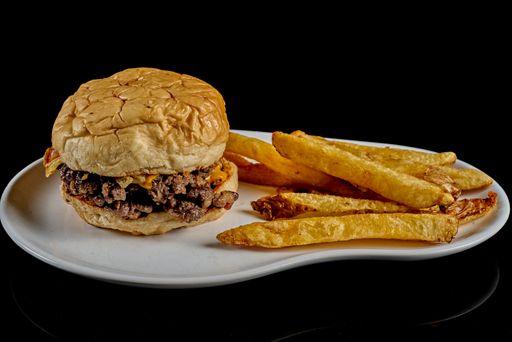 A closeup shot of burger and chips on a white plate isolated on black background - food menu