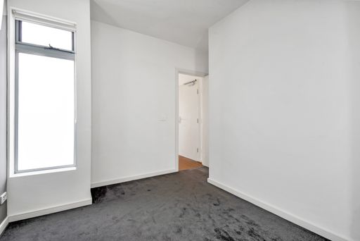 An empty room with white walls and gray fabric carpet