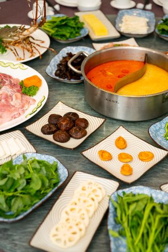 A vertical shot of a soup and side dishes with leaf vegetable and spices