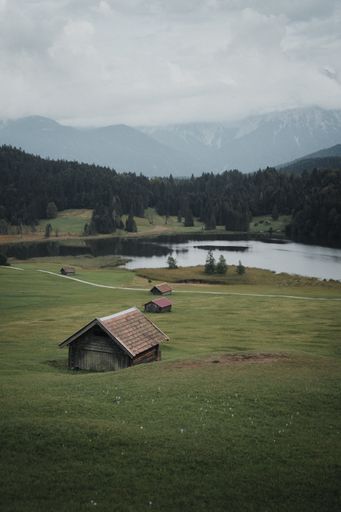 A beautiful landscape with small wooden houses by the lake and lush green trees in the background