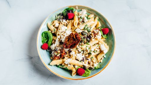 A top view of the fresh delicious cheesy penne pasta with spinach in the bowl on the marble surface