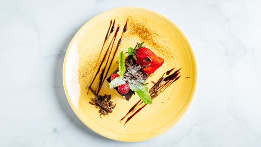 A  piece of creamy chocolate cake decorated with raspberries and strawberries on the plate