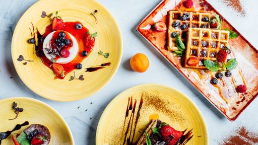 A top view of the various fresh and delicious desserts on the plates on the marble surface
