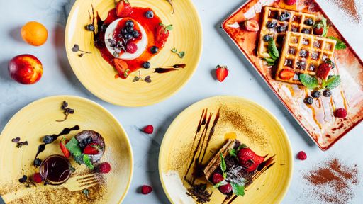 A top view of the various fresh and delicious desserts on the plates on the marble surface