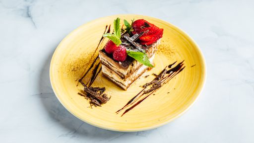 A closeup of a piece of creamy chocolate cake decorated with raspberries and strawberries on the plate