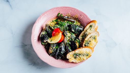 A  bowl of delicious and fresh mussels with sliced bread tomatoes covered in cheese