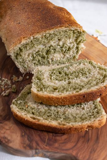 A loaf of bread sliced with two pieces missing on a wooden cutting board