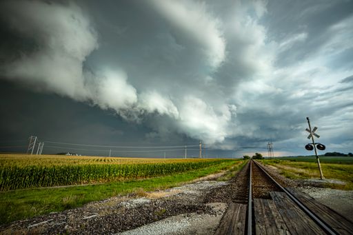 A massive tornado looms in the distance over the Illinois railroad track