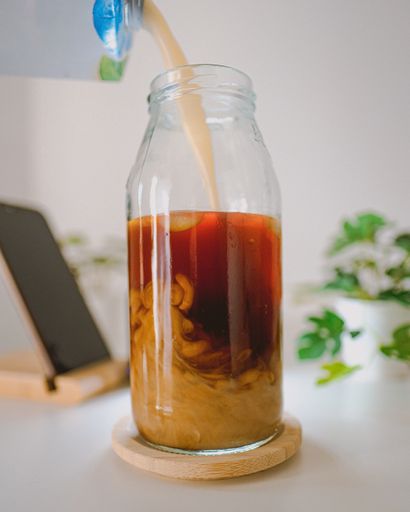 A closeup shot of an iced coffee mixing with a plant based milk