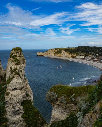 A scenic view of Falaise d'Aval cliff under a cloudy blue sky