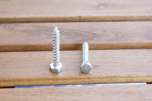 A closeup shot of two metal screws on a wooden surface