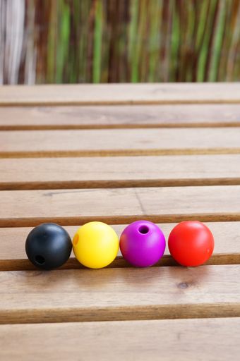 A vertical closeup shot of colorful beads on a wooden surface