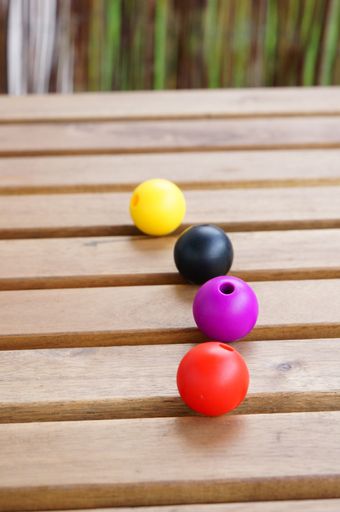 A vertical closeup shot of colorful beads on a wooden surface