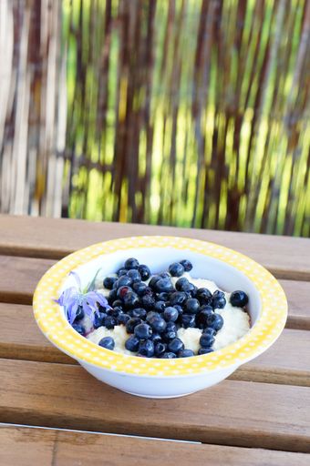 A vertical closeup shot of a Semolina dessert with blueberries on a wooden table