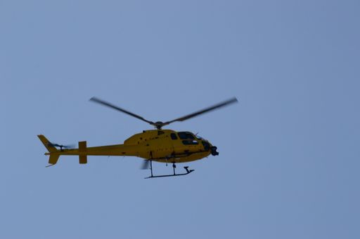 Yellow helicopter flying in the deep blue sky over Barcelona, Spain, Europe