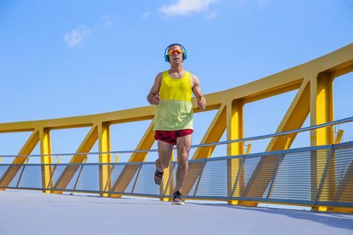 A Young Caucasian athlete running down a yellow bridge outdoors.