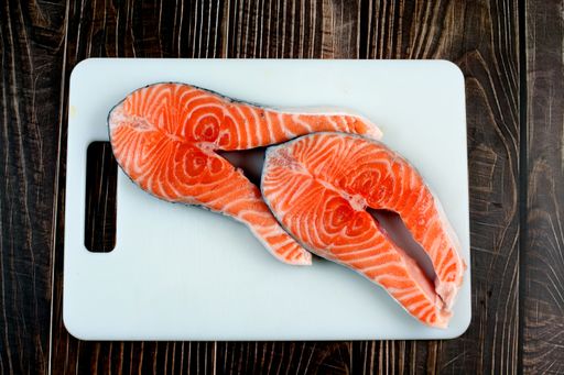 Two pieces of delicious salmon on a white chopping board