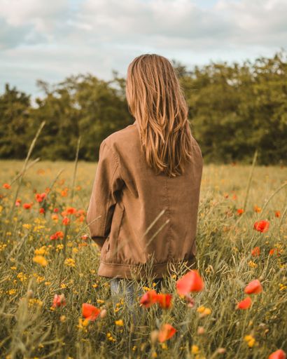 A young male standing in a poppy field on a sunny day