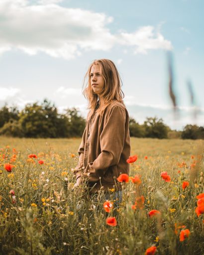 A young Caucasian male standing in a poppy field on a sunny day