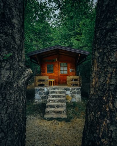 A vertical shot of a red house with stone stairs in a forest